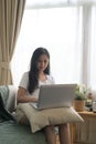 Millennial woman sitting on couch in living room and using laptop. Royalty Free Stock Photo