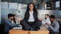 Smiling mindfulness businesswoman happy leader woman sitting at table in lotus position meditating in office meeting Royalty Free Stock Photo