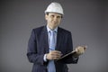 Smiling mining engineer in hard hat makes notes on clipboard and looks at camera Royalty Free Stock Photo