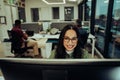 Smiling mixed race business woman wearing spectacles working late hours in office finishing report typing on desktop