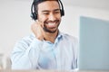 Smiling mixed race male call centre agent smiling while wearing a wireless headset. Young man working as a customer Royalty Free Stock Photo