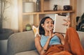 Smiling mixed race woman browsing internet on digital tablet at home. Happy hispanic lying down on living room sofa Royalty Free Stock Photo