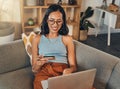 Smiling mixed race woman using credit card for ecommerce on laptop at home. Happy hispanic sitting alone on living room Royalty Free Stock Photo
