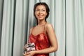 Smiling mixed race young woman wearing evening dress holding celebratory gift