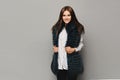 Smiling model girl in winter fur vest posing on the grey background, isolated. Winter fashion