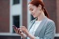 Smiling modern Caucasian young woman using a smartphone