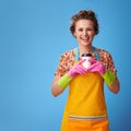Smiling modern housewife holding coffee cup on blue