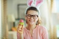 Smiling modern housewife with glasses holding easter egg
