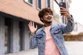 Smiling modern Indian man taking selfie, having video call on the street. Emotional asian influencer recording video,