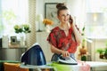 Woman ironing while using phone in modern house in sunny day Royalty Free Stock Photo
