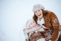 Smiling modern mother and daughter laying in snow Royalty Free Stock Photo