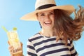 Smiling modern woman against blue sky with refreshing cocktail Royalty Free Stock Photo