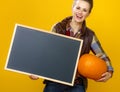 Smiling modern woman farmer with pumpkin showing blank board Royalty Free Stock Photo