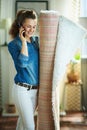Woman with carpet talking on phone in modern house in sunny day Royalty Free Stock Photo