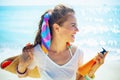 Smiling woman with orange sunblock bottle and beach straw bag