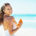 Smiling young woman on beach applying sun block creme Royalty Free Stock Photo