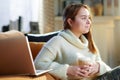 Smiling modern young woman with cup of hot beverage and laptop Royalty Free Stock Photo