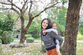 Smiling mom carrying her little child girl in garden with fully fall pink flower around. Happy loving family Royalty Free Stock Photo