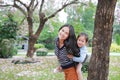 Smiling mom carrying her little child girl in garden with fully fall pink flower around. Happy loving family Royalty Free Stock Photo