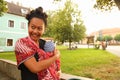 Smiling mom carrying newborn baby boy in cloth outdoor