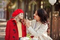 Smiling mom helps little cute daughter fasten her red coat
