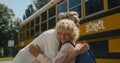 Smiling mom hugging son near school bus. Boy saying goodbye to cheerful mother. Royalty Free Stock Photo