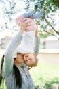 Smiling mom lifts her little girl upside down and kisses her on the cheek Royalty Free Stock Photo