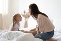 Smiling mom and little daughter have fun in bedroom