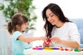 Smiling mom and little daughter sculpt red heart of plasticine. Child development and creativity. Family love, happy childhood