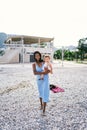 Smiling mom walking along pebble beach with little girl in her arms Royalty Free Stock Photo