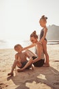 Smiling Mother and adorable children sitting on a sandy beach Royalty Free Stock Photo