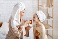 Smiling mother applying cream on her cute daughter`s face, arranging home beauty salon, having spa day together Royalty Free Stock Photo