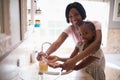 Smiling mother assisting daughter while washing hands in bathroom at home