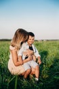 Smiling mother and baby sitting on meadow