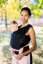 Smiling mother with baby in sling in park Royalty Free Stock Photo