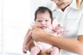 Smiling mother carrying of her newborn baby girl at home. Cute 19 days Asian Australian infant baby looking at camera, smiling. Royalty Free Stock Photo