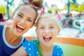 Smiling mother and child tourists in theme park having ride