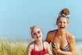 Smiling mother and child use lipstick with spf on seacoast