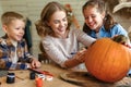 Smiling mother with children creating jack-o-lantern during Halloween celebration at home Royalty Free Stock Photo