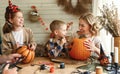 Smiling mother with children creating jack-o-lantern during Halloween celebration at home