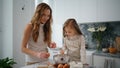 Smiling mother daughter breaks eggs at kitchen. Child mixing ingredients at bowl Royalty Free Stock Photo