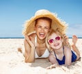 Smiling mother and daughter laying on beach under big straw hat Royalty Free Stock Photo