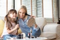 Smiling Mother and Daughter looking in the mirror and applying cosmetic with brushes on the cheeks. Young woman and kid girl doing Royalty Free Stock Photo