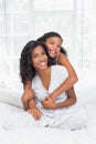 Smiling mother and daughter posing together on bed