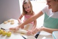 Smiling mother and daughter roll out dough with rolling pin closeup Royalty Free Stock Photo