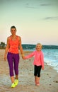 Smiling mother and daughter on seashore in evening walking Royalty Free Stock Photo