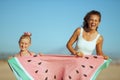 Smiling mother and daughter showing funny watermelon towel