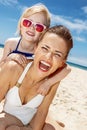 Smiling mother and daughter in swimsuits at sandy beach Royalty Free Stock Photo