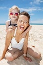 Smiling mother and daughter in swimsuits at sandy beach Royalty Free Stock Photo