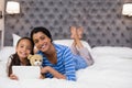 Smiling mother and daughter using digital tablet while lying on bed at home Royalty Free Stock Photo